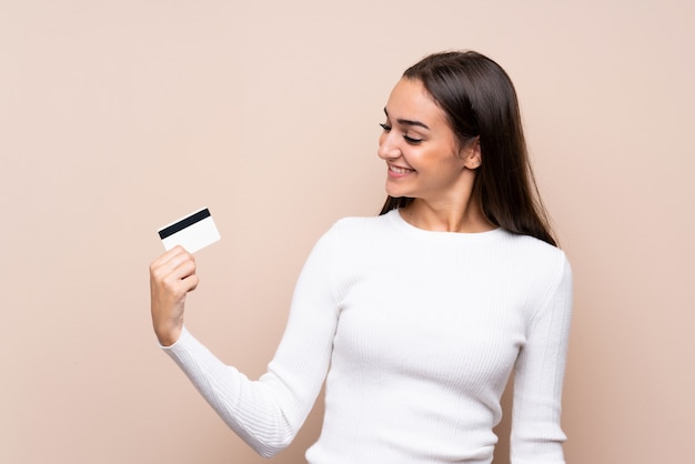 クレジットカードを保持している孤立した背景の上の若い女性