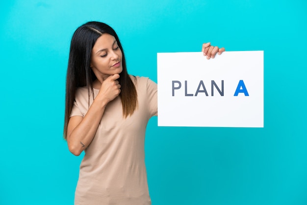 Young woman over isolated background holding a placard with the message PLAN A and thinking