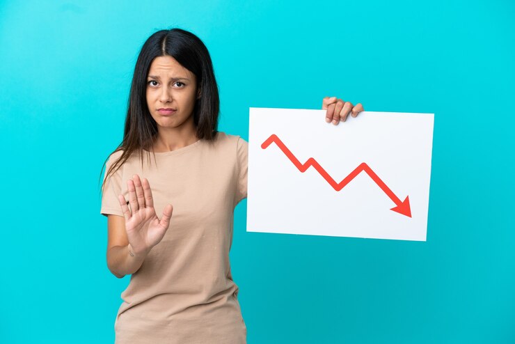 फोटो young woman over isolated background holding a sign with a decreasing statistics arrow symbol and doing stop sign