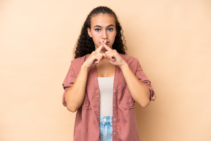 Photo young woman isolated on beige background showing a sign of silence gesture
