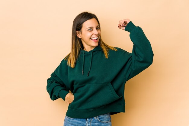 Young woman isolated on beige space cheering carefree and excited. Victory concept.