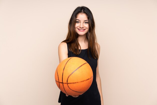 Young woman isolated on beige wall playing basketball