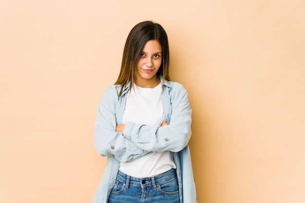 Young woman isolated on beige wall who is bored, fatigued and need a relax day.