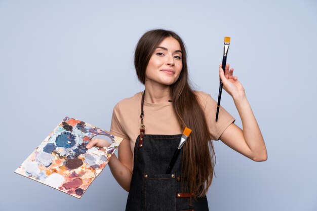 Young woman over isolated blue background holding a palette