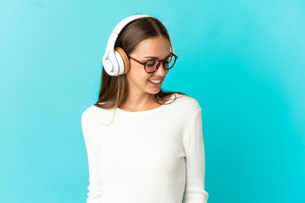 Young woman over isolated blue background listening music