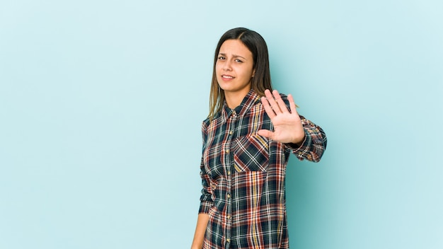 Young woman isolated on blue background rejecting someone showing a gesture of disgust.