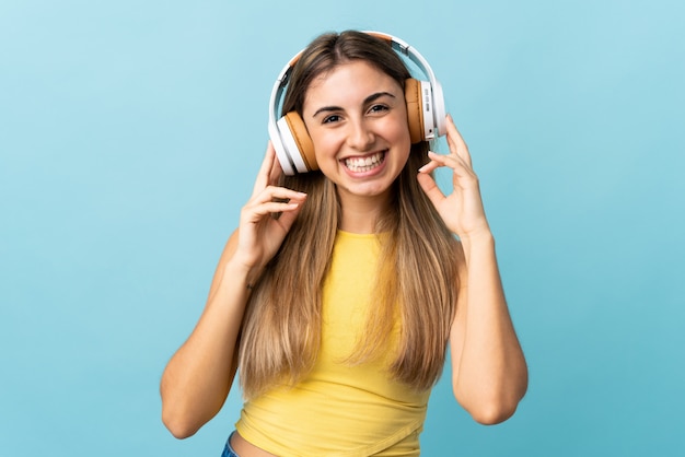 Young woman on isolated blue listening music