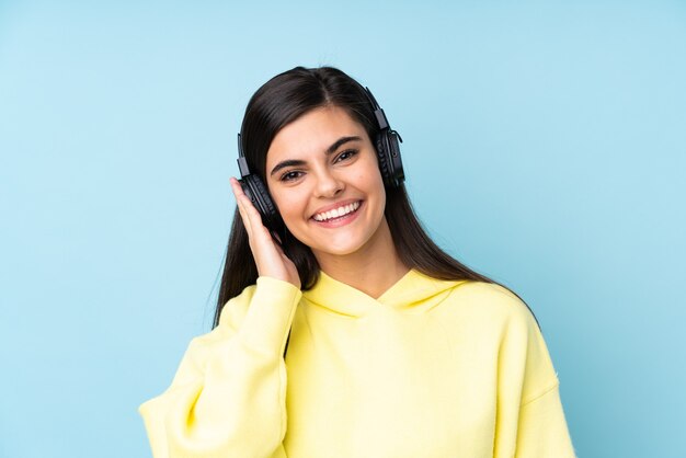 Young woman over isolated blue listening music