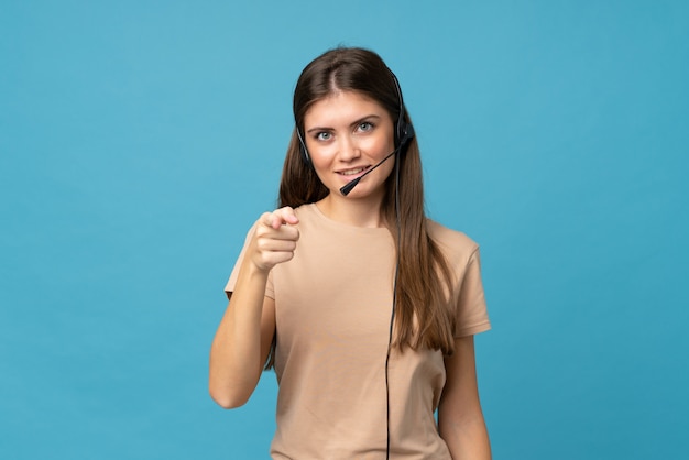 Young woman over isolated blue  pointing to the front