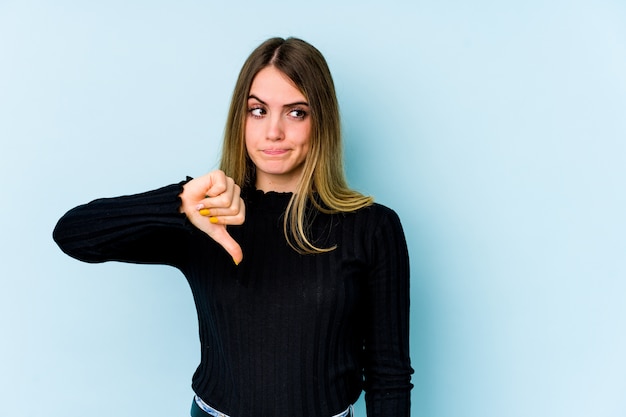 Young woman isolated on blue showing thumb down