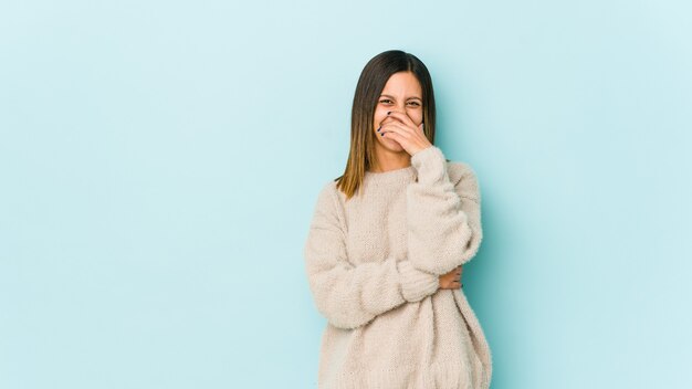 Young woman isolated on blue space laughing happy, carefree, natural emotion.