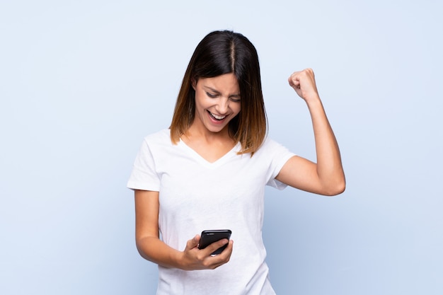 Young woman over isolated blue  using mobile phone