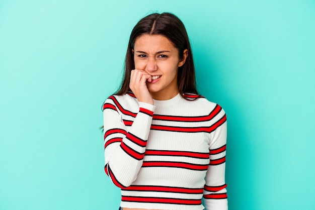 Young woman isolated on blue wall biting fingernails, nervous and very anxious