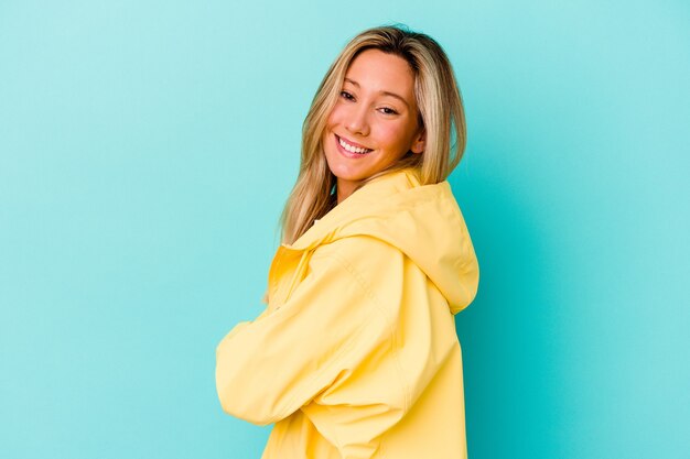 Young woman isolated on blue wall happy, smiling and cheerful