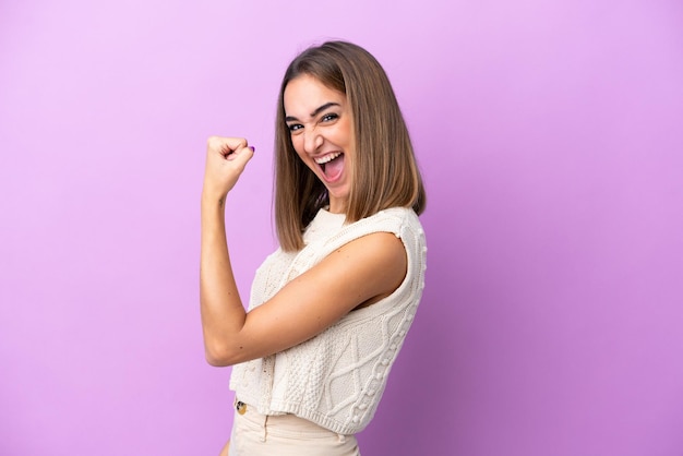 Young woman over isolated blue wall holding a camera