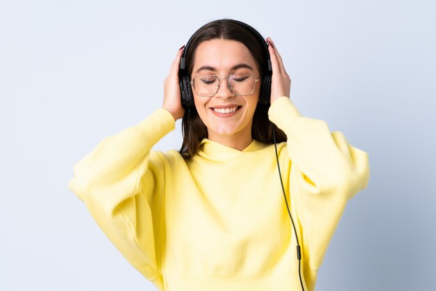 Giovane donna sopra musica d'ascolto isolata della parete blu