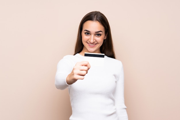 Young woman over isolated  holding a credit card