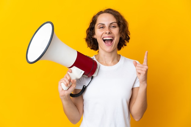 Young woman isolated holding a megaphone and pointing up a great idea