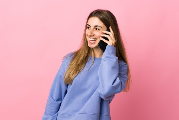 Молодая женщина на розовом, держа разговор с мобильным телефоном с кем-то