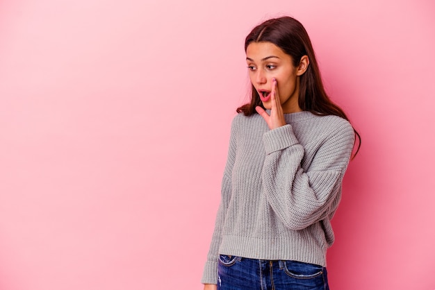 Young woman isolated on pink wall being shocked because of something she has seen