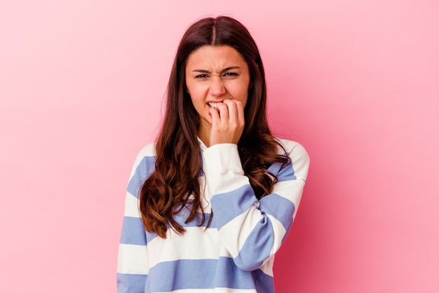 Young woman isolated on pink wall biting fingernails, nervous and very anxious