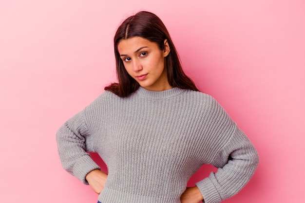 Young woman isolated on pink wall confused, feels doubtful and unsure