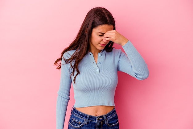 Young woman isolated on pink wall having a head ache, touching front of the face