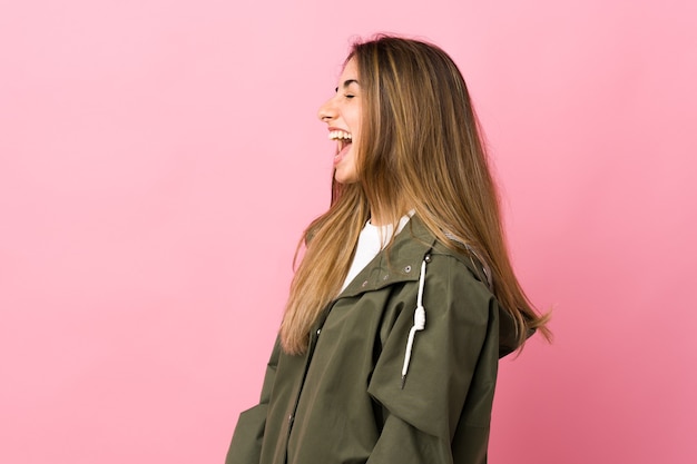 Young woman over isolated pink wall laughing in lateral position