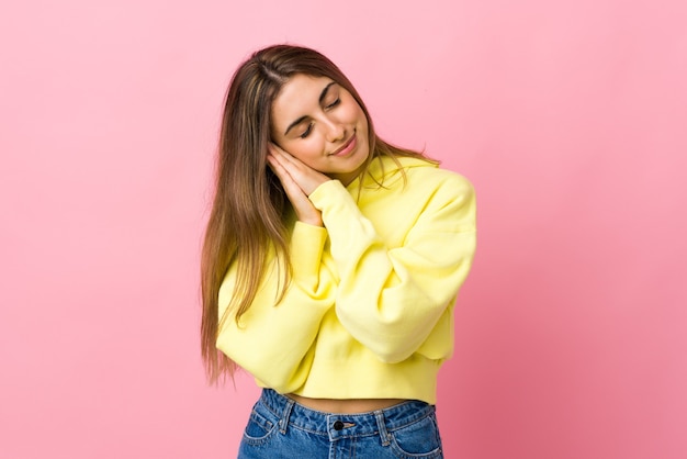 Giovane donna sopra la parete rosa isolata che fa gesto di sonno nell'espressione dorable