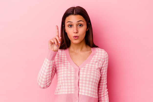 Young woman isolated on pink wall pointing upside with opened mouth