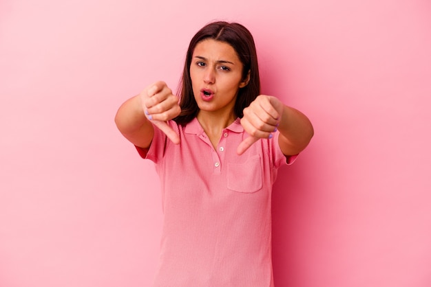 Young woman isolated on pink wall showing thumb down and expressing dislike