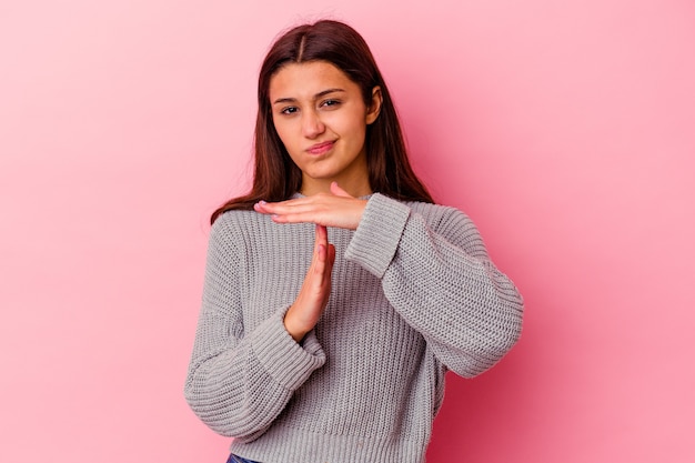 Young woman isolated on pink wall showing a timeout gesture