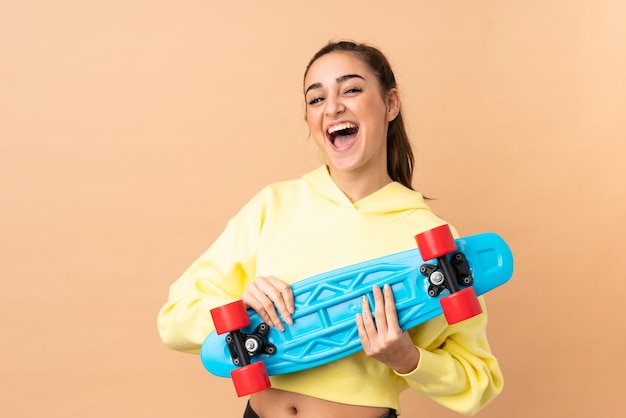 Young woman isolated on pink wall with a skate with happy expression