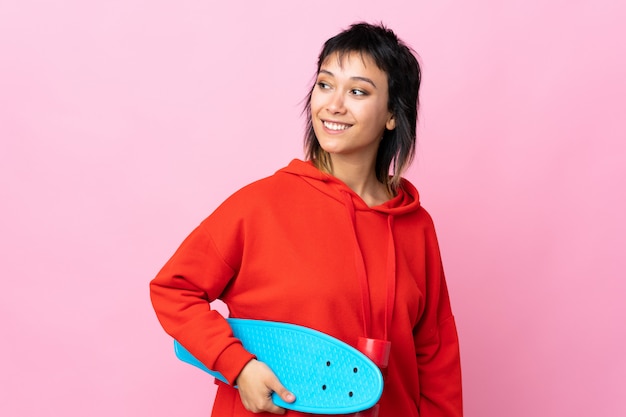 Young woman over isolated pink with a skate