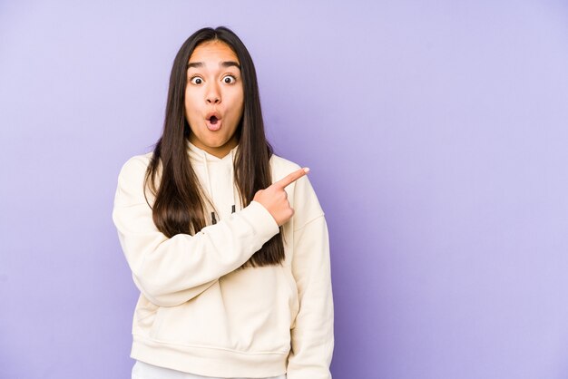 Young woman isolated on a purple pointing to the side