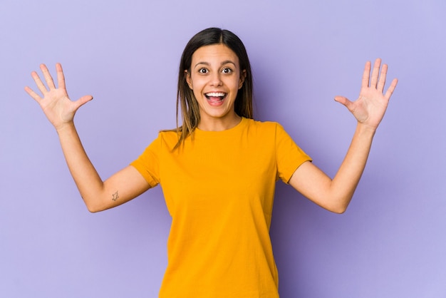 Young woman isolated on purple receiving a pleasant surprise, excited and raising hands.