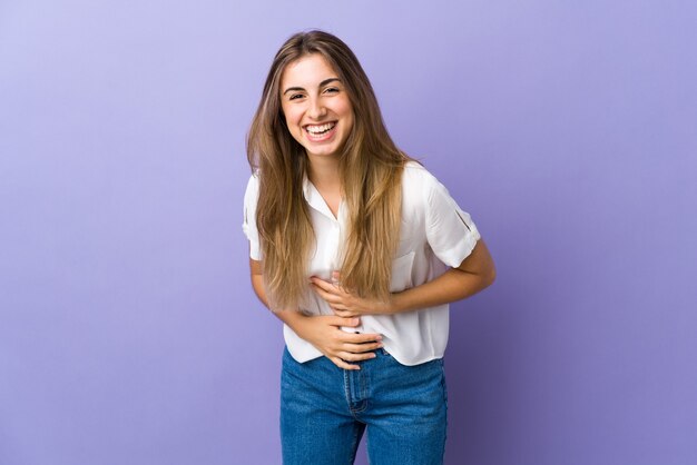 Young woman on isolated purple smiling a lot