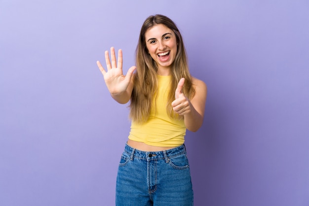 young woman over isolated purple wall counting six with fingers