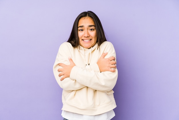 Young woman isolated on a purple wall going cold due to low temperature or a sickness