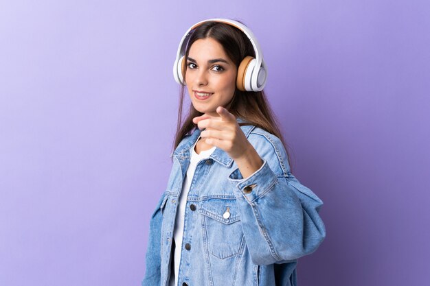 보라색 벽 음악 듣기와 앞을 가리키는에 고립 된 젊은 여자