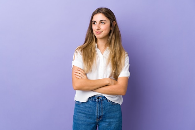 Young woman over isolated purple wall looking to the side