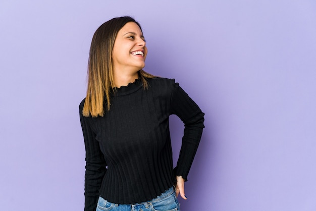 Young woman isolated on purple wall relaxed and happy laughing, neck stretched showing teeth.