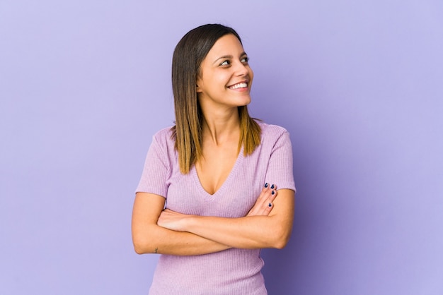 Young woman isolated on purple wall smiling confident with crossed arms.