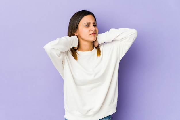 Young woman isolated on purple wall suffering neck pain due to sedentary lifestyle.