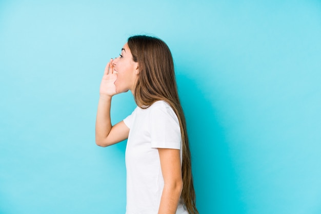 Young woman  isolated shouting and holding palm near opened mouth