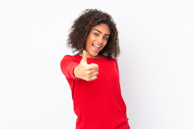 Young woman isolated on wall with thumbs up because something good has happened