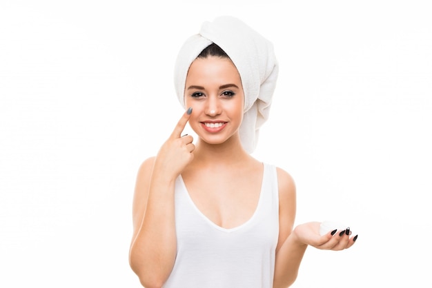 Young woman over isolated white background with moisturizer
