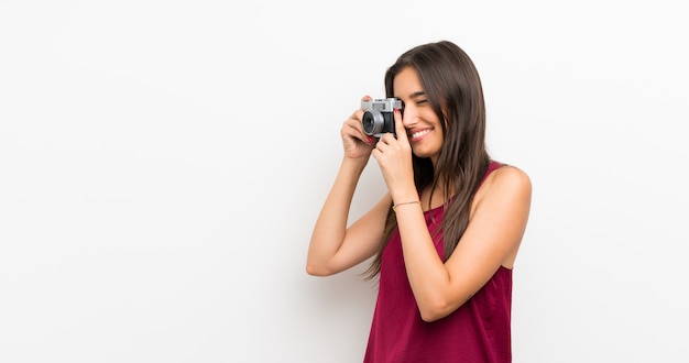 Young woman over isolated white holding a camera