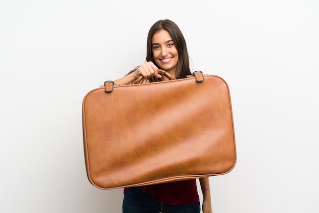 Young woman over isolated white holding a vintage briefcase