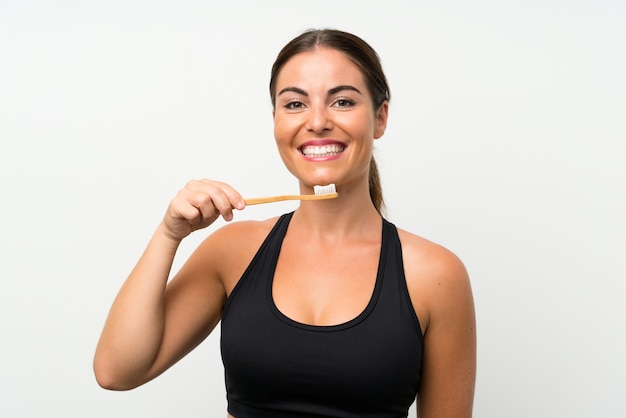 Young woman over isolated white wall brushing her teeth